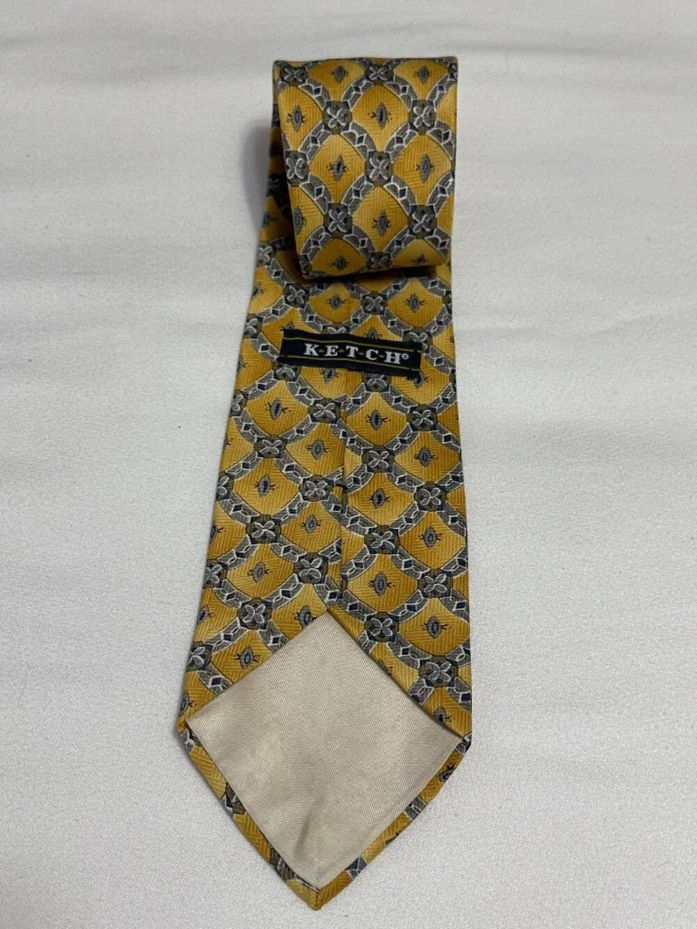 This is a vintage Ketch geometric medallion silk necktie, featuring a distinct g